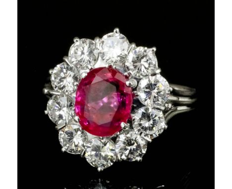 A modern silvery coloured metal mounted ruby and diamond ring, the oval cut ruby 1.66ct bordered by ten brilliant cut diamond