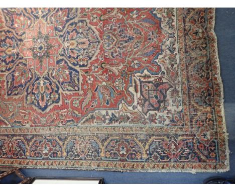 A NORTH PERSIAN CARPET with a brick red ground and a central floral medallion, 282cm x 195cm, fading throughout and wear conc