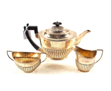 A Silver three piece tea set, teapot and cream jug, Sheffield 1914, a sucrier, London 1914, with inscriptions to all