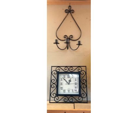 A decorative wall clock and candle sconce