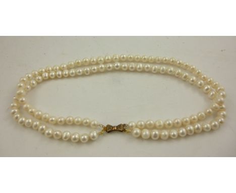 A DOUBLE ROW OF UNIFORM FRESHWATER PEARLS with gilt metal bow clasp, 40cm long 