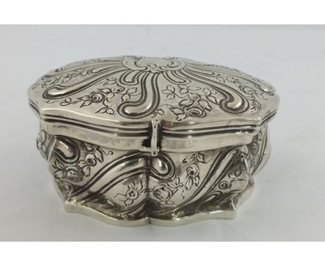 A FOREIGN SILVER COLOURED METAL TRINKET BOX having fancy floral worked top with un-engraved cartouche, lobed worked body and 