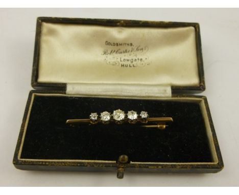 AN EDWARDIAN DIAMOND BAR BROOCH, having five graduated old cushion cuts in a white metal claw setting with gold bar and pin b