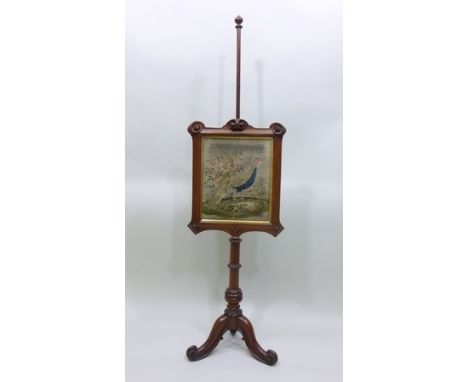 A MID VICTORIAN MAHOGANY FIRESCREEN having panel with beadwork inset of a peacock and scroll surround, turned dog tooth ringe