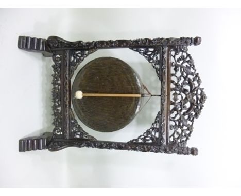 A LATE 19TH CARVED ORIENTAL DINNER GONG having ornate bird and floral carved surround and bronze gong, 94cm x 60cm 