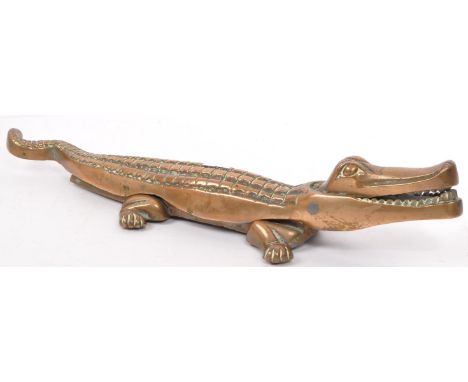 A vintage 20th century cast iron nut cracker in the form of a crocodile. In a standing position with a curved tail and textur