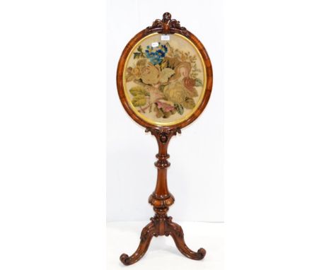 = A Victorian walnut pole screen, with oval needlework panel, raised on three cabriole legs
