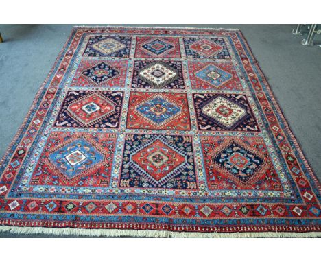 Yalameh carpet, the indigo and ivory compartmentalised field of hooked medallions framed by narrow borders, 257cm by 204cm 