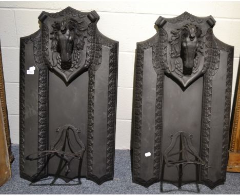 A pair of cast iron saddle racks surmounted by horse`s heads