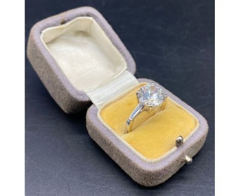 18ct white gold solitaire ring. The brilliant round cut stone with tapering baguette to each shoulder to each shoulder. Ring 