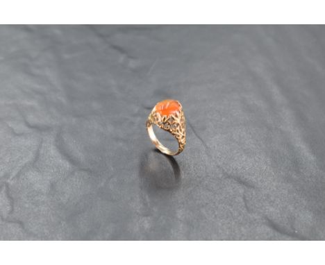A yellow metal and agate ring, the domed cabochon within a pierced foliate, surround, the shank unmarked, ring size M, 4.1gra