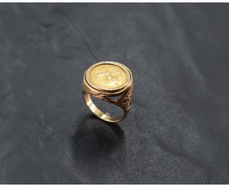 A 9ct gold mounted 1/10 Krugerrand coin ring, dated 1983, within an engine-turned setting and pierced and moulded surround/sh