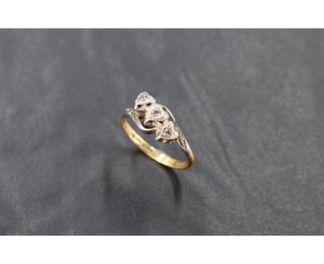 An 18ct gold and diamond three stone ring, the three small diamond brilliants illusion-set within heart-shaped surrounds, and