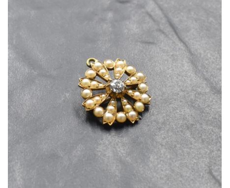 An Edwardian yellow metal pendant/brooch of circular form having a central old cut diamond, approx 0.5ct in a seed pearl surr