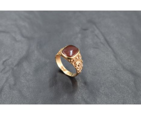 A 9ct gold and red agate signet ring, the rounded rectangular red agate matrix between scroll moulded shoulders, marked 375 t