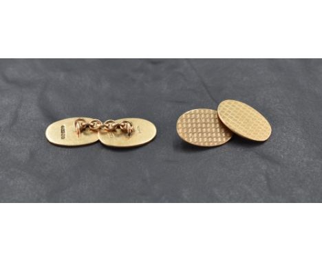 A pair of 9ct gold cufflinks of oval form having engine turned chequered decoration and chain connectors, approx 8.6g