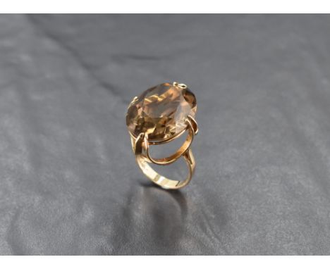 An oversized facet-cut oval smoky quartz ring in a claw-set basket mount, on a 9ct gold loop, size O &amp; approx 10g