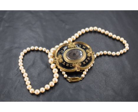 A Victorian mourning brooch bearing a central hair locket in a black enamel and pinchbeck mount, and a string of Lotus gradua