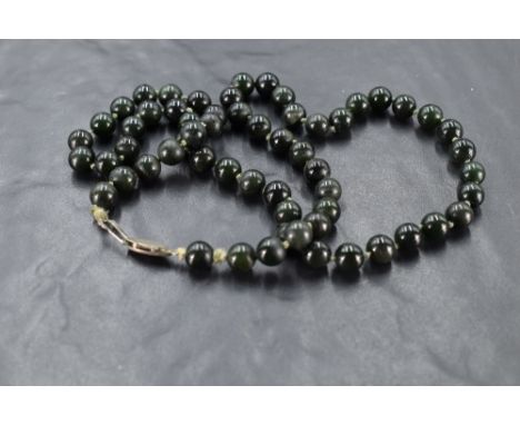 A string of Jade style dark green beads of even form, approx 23'