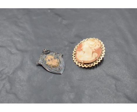 A conch shell cameo brooch depicting a maiden in profile in a decorative 9ct gold mount and a silver 1930's sports medalion a