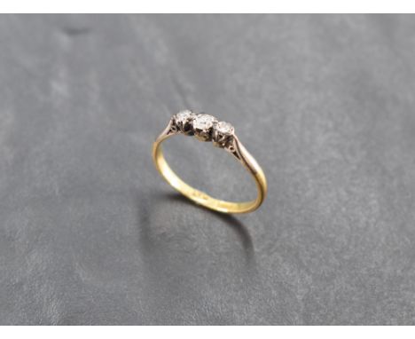 A diamond trilogy ring having three small diamonds in illusionary mounts on a yellow metal loop stamped 18ct, size L &amp; ap