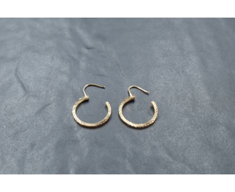 A pair of yellow metal earrings, of circular form with hinged clasps and engine-cut fluted decoration, unmarked, 1.9grams