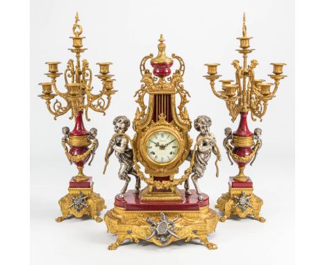 A 3 piece garniture clock in empire style and finished with red marble. The second half of the 20th century. Height candleabr