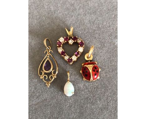 FOUR 9ct GOLD PENDANTS, THREE WITH FULL HALLMARKS ONE WITH NO ASSAY MARKS TO INCLUDE AN ENAMEL LADYBIRD, A RED AND WHITE STON