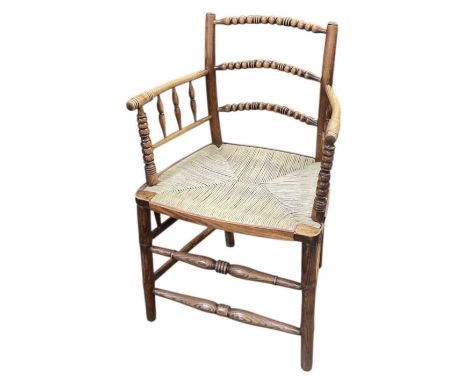 A 19th century oak bobbin turned rush seated elbow chair of small proportions, width 54cm.