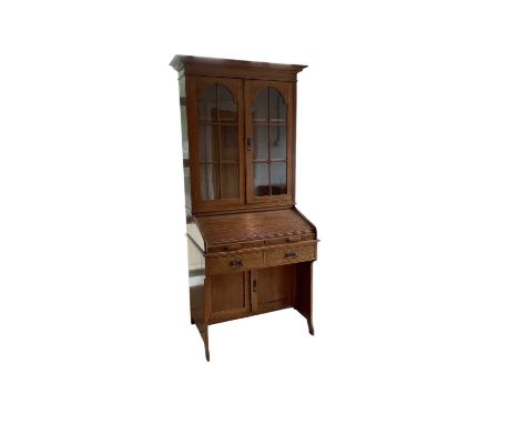 An early 20th century oak roll top bureau bookcase, with pair of glazed doors above roll tambour top enclosing fitted interio