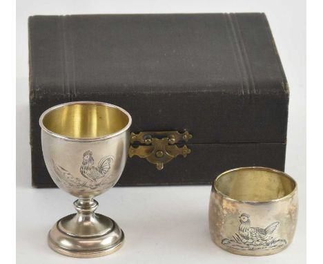 A cased German 800 grade silver christening set, comprising egg cup, napkin ring and spoon, all engraved with decoration of a