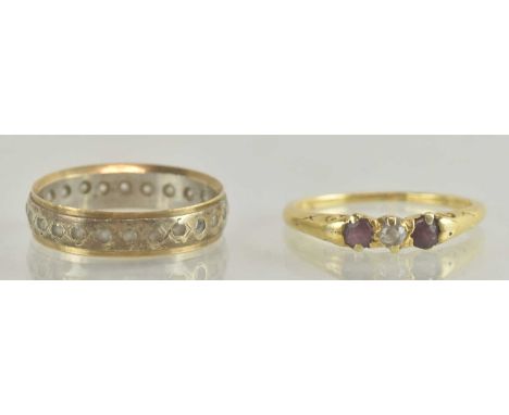 An 18ct yellow gold ruby and diamond set three stone ring, the central round brilliant cut diamond flanked by two small round