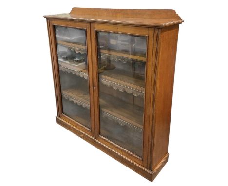 A late 19th/early 20th century oak bookcase, with pair of glazed doors enclosing three adjustable wooden shelves, width 131cm