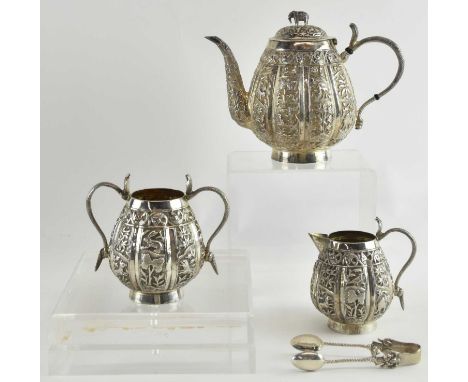 An Indian white metal three piece tea service, decorated with animals, fish and landscape, comprising teapot, milk jug, twin 