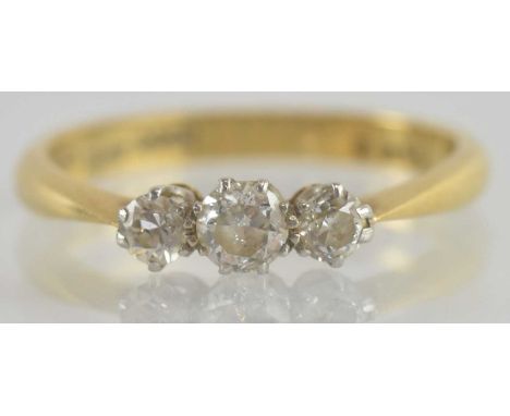 An 18ct gold three stone diamond ring, the central stone flanked by two smaller stones in platinum claw setting, size M/N, ap