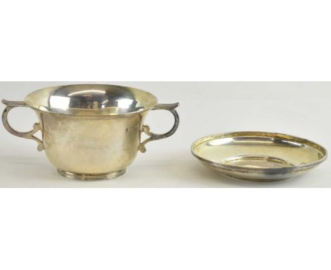 A late Victorian hallmarked silver twin handled cup and saucer, London 1897, inscribed 'E. M. Wood, May 9th 1974' and 'A. F. 