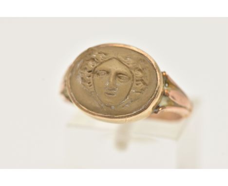 A 9CT GOLD LAVA CAMEO RING, oval cameo depicting the face of Medusa, collet set to the trifurcated shoulders, leading onto a 