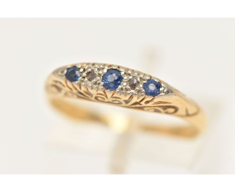 A YELLOW METAL SAPPHIRE AND DIAMOND RING, set with three circular cut blue sapphires, and two rose cut diamonds, scrolling ga