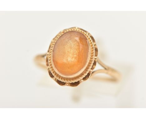 A YELLOW METAL CITRINE RING, set with an oval cut citrine in a collet setting with rope twist surround and scalloped edge, bi