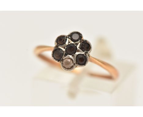 A YELLOW METAL CLUSTER RING, flower shape cluster set with six circular cut brown stones and one colorless circular cut stone
