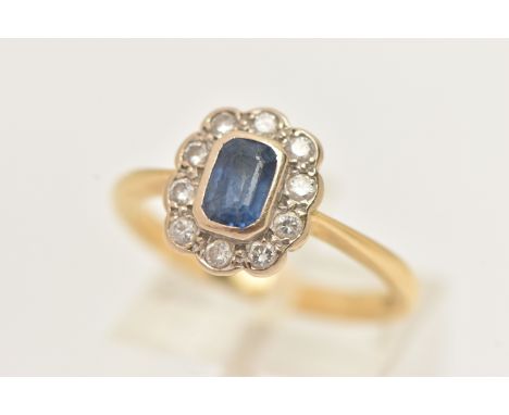 AN 18CT GOLD SAPPHIRE AND DIAMOND CLUSTER RING, centering on an emerald cut blue sapphire, collet setting, in a surround of r