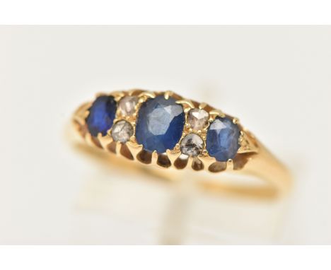 A YELLOW METAL GEM SET RING, set with three oval cut blue sapphires, and four rose cut diamonds, open work gallery, leading o