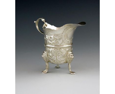 An 18th century Irish silver cream jug, maker's mark probably SW, Dublin, helmet form, embossed decoration on a matted backgr