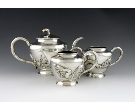 λA three-piece Chinese silver tea set, by Leun Hing, Shanghai circa 1910, tapering circular form, applied with dragons, simul