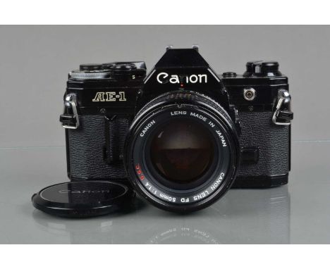 A Canon AE-1 SLR Camera, black, serial no 988052, shutter working, meter responsive, self timer working, body G, some wear to