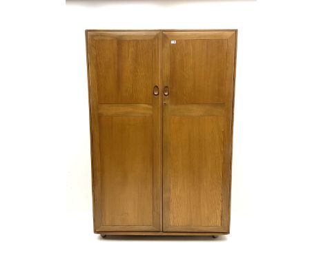 Ercol double wardrobe, two fielded doors enclosing hanging rail, raised on castorsDimensions: Height:&nbsp;183cm&nbsp; Length