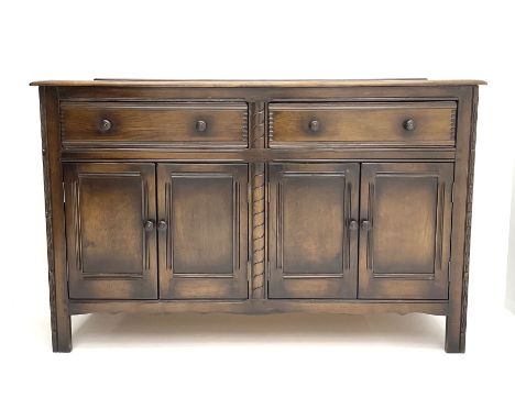 Ercol elm sideboard, fitted with two long drawers above two double panelled cupboard doors enclosing shelving, raised on carv