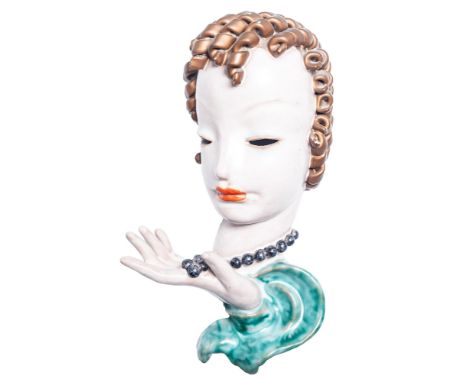 AN INTER-WAR YEARS GOLDSCHEIDER (VIENNA) GLAZED RED EARTHENWARE WALL MASK  in the form of a female head, with ringlet hair, h