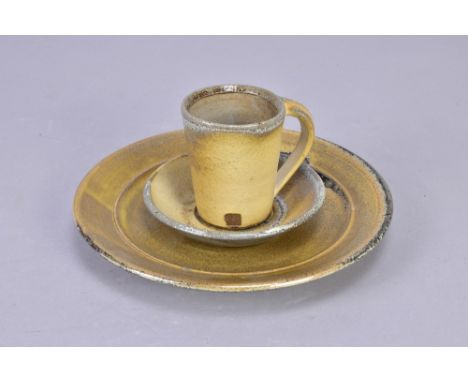 JACK DOHERTY (born 1948) for Leach Pottery; a stoneware trio comprising a plate, cup and saucer, impressed pottery marks, pla