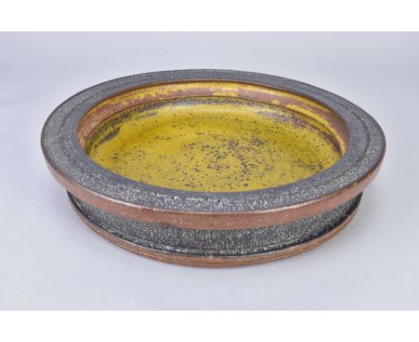 ROBIN WELCH (1936-2019); a stoneware bowl with stepped rim and mustard glaze to the well, painted signature, diameter 34.5cm.